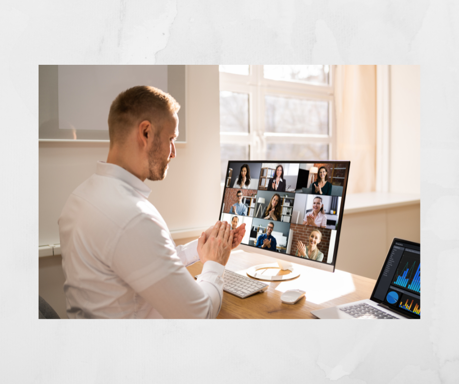 Man sits at desk during a virtual meeting with colleagues on a computer screen